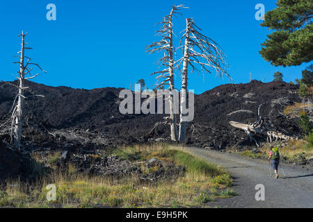 Hiker on the gravel road through the lava field from 2002, Mount Etna, in Mascali, Sicily, Italy Stock Photo
