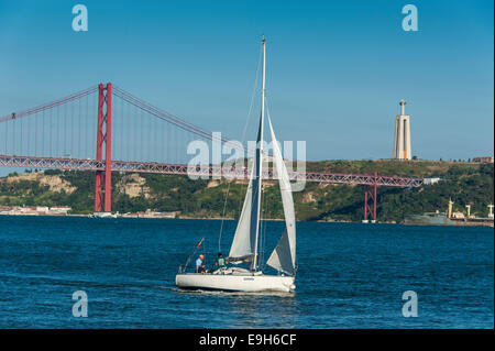 Sailing boat on the Tagus River in front of the Ponte 25 de Abril suspension bridge, Belém, Lisbon, Lisbon District, Portugal Stock Photo