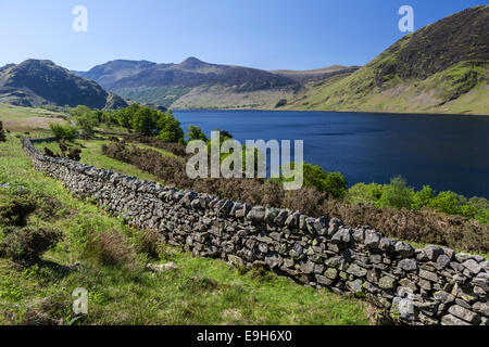 View over an old English stone wall towards the blue lake of Crummock Water, Lake District National Park, Cumbria, England Stock Photo