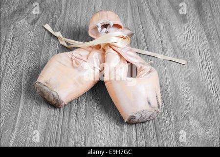 Old used  ballet pointe shoes on vintage wooden background Stock Photo