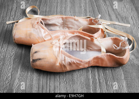Old used  ballet pointe shoes on vintage wooden background Stock Photo