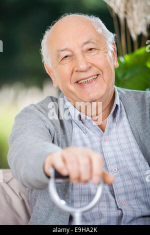 Portrait Of Smiling Senior Man Holding Walking Stick Stock Photo