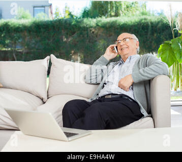 Relaxed Senior Man Using Mobilephone On Couch Stock Photo