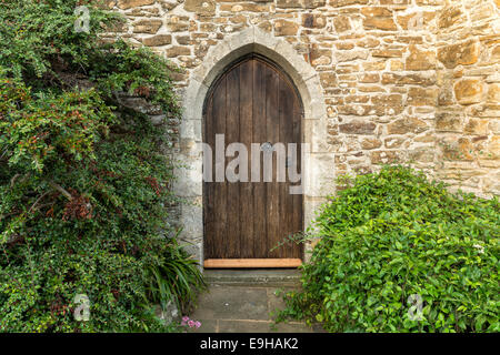 An old arched heavy wooden door set in an ancient stone wall Stock Photo