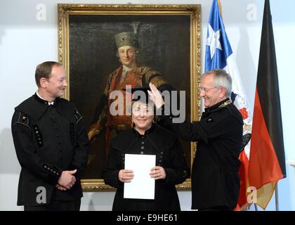 Freiburg, Germany. 28th Oct, 2014. Chilean President Michelle Bachelet is given her honorary doctorate from the TU mining academy Freiberg by the rector, Bernd Meyer (R), and dean, Carsten Drebenstedt, in the University Senate Assembly Hall in Freiberg, Germany, 28 October 2014. The awarding of the degree takes places during the Chilean President's visit to Germany. Credit:  dpa picture alliance/Alamy Live News Stock Photo