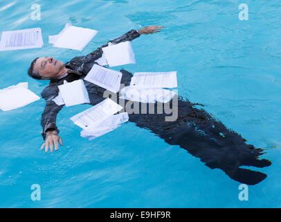 Senior man floating among papers in water Stock Photo