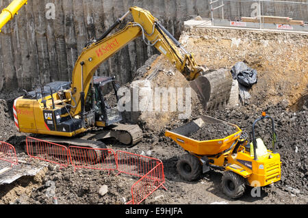 A Caterpillar hydraulic excavator filling a Thwaites Alldrive 6 tonne front tipper truck with spoil. Stock Photo