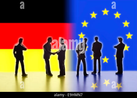 Model figures symbolizing the politicians are faced with the flags of Germany and the EU. Two of them shake hands. Digital Composite (DC) Stock Photo