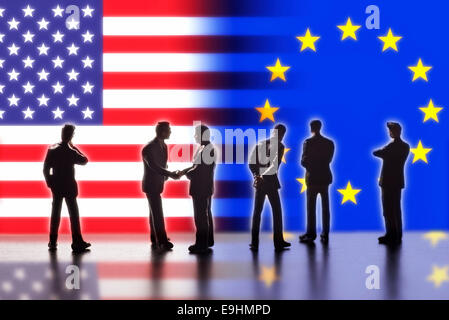 Model figures symbolizing the politicians are faced with the flags of the USA and the EU. Two of them shake hands. Digital Composite (DC) Stock Photo