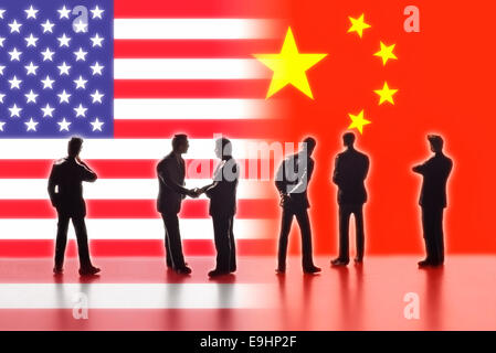 Model figures symbolizing the politicians are faced with the flags of the USA and China. Two of them shake hands. Digital Composite (DC) Stock Photo