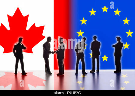 Model figures symbolizing the politicians are faced with the flags of the USA and the EU. Two of them shake hands. Digital Composite (DC) Stock Photo