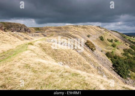 Cracken edge quarries near Chinley in Derbyshire. Sunlight on the edge with a moody sky overhead. Stock Photo