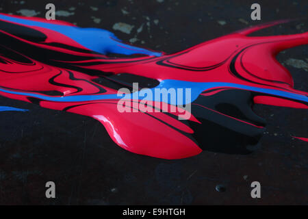 Blue, red and black paints swirled over a dark metallic background Stock Photo