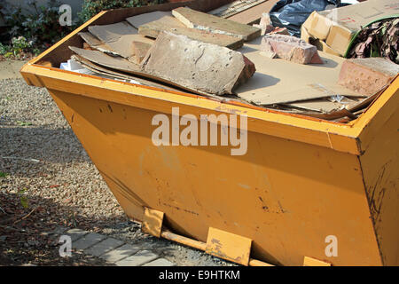 Close-up of yellow skip full of concrete and rubbish symbolizing construction, home renovations and environmental waste Stock Photo