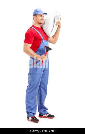 Full length portrait of a male plumber carrying a toilet and holding a plunger isolated on white background Stock Photo