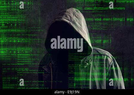 Faceless hooded anonymous computer hacker with programming code from monitor Stock Photo