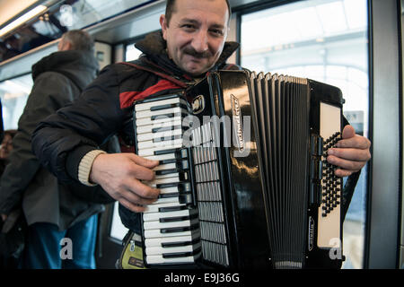 an accordion player busks on the paris metro trains with a traditional wind instrument Stock Photo