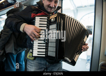 an accordion player busks on the paris metro trains with a traditional wind instrument Stock Photo