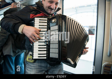 an accordion player busks on the paris metro trains with a traditional wind instrument Stock Photo