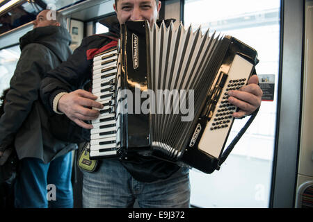 an accordion player busks on the paris metro trains with a traditional wind instrument Stock Photo