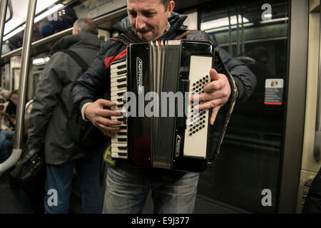 an accordion player busks on the paris metro trains with a traditional wind instrument Stock Photo