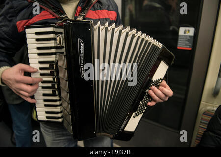 an accordion player busks on the paris metro trains with a traditional wind instrument Stock Photo