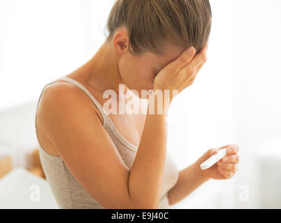 Frustrated young woman with pregnancy test Stock Photo