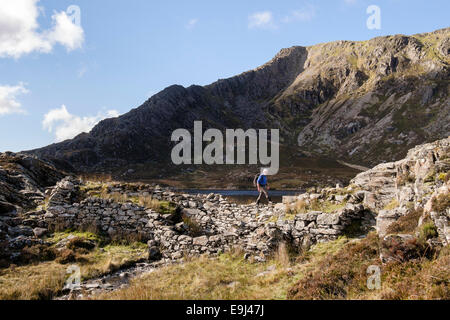 Hiker on Llyn Y Foel lake dam below Daear Ddu east ridge to Carnedd Moel Siabod mountain summit in Snowdonia Wales UK Stock Photo