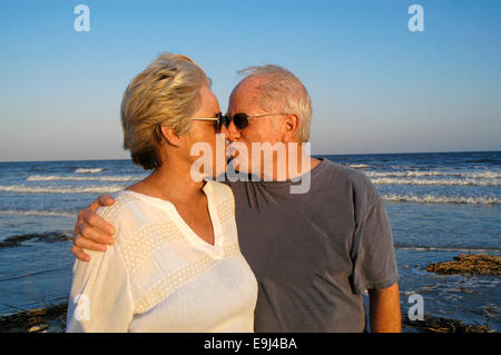 Senior Couple on Beach: Portrait of a senior husband and wife couple on the beach in front of the ocean at sunset. Stock Photo
