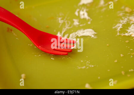 red childs plastic fork and green plastic plate with finished meal Stock Photo