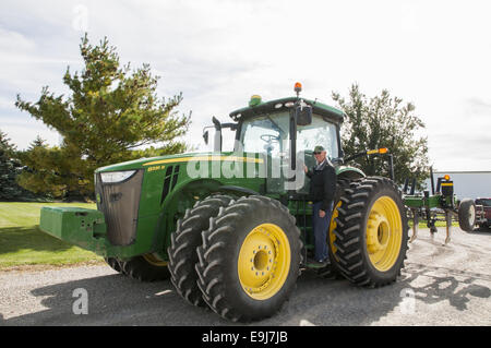 John Deere 8335R tractor with ripper implement.  Mature man preparing to enter tractor cab. Stock Photo