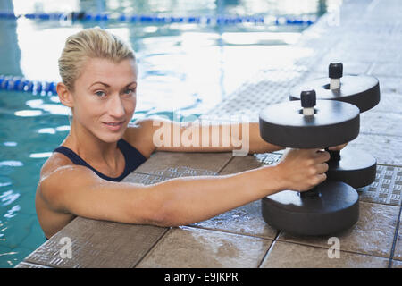 Female swimmer with foam dumbbells in swimming pool Stock Photo