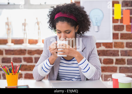 Interior designer drinking coffee at desk Stock Photo