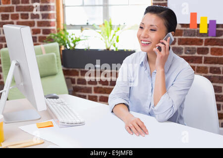 Female executive using mobile phone at desk Stock Photo
