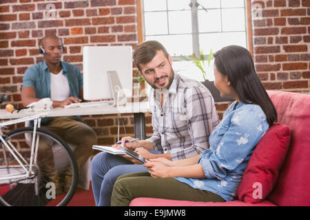 Casual colleagues using digital tablets on couch Stock Photo