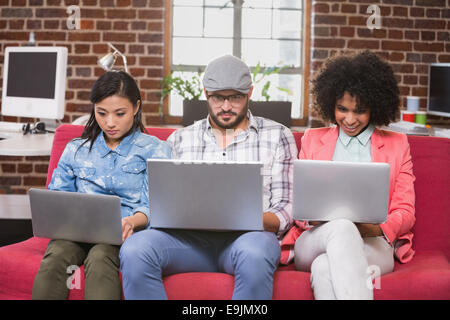 Colleagues using laptops on couch Stock Photo