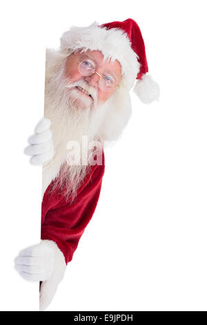 Santa looks out behind a wall Stock Photo