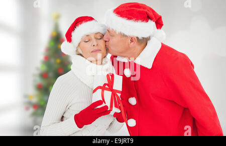 Composite image of festive mature couple holding gift Stock Photo