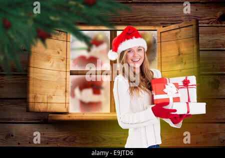 Composite image of festive blonde holding pile of gifts Stock Photo