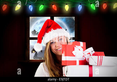 Composite image of festive blonde holding pile of gifts Stock Photo