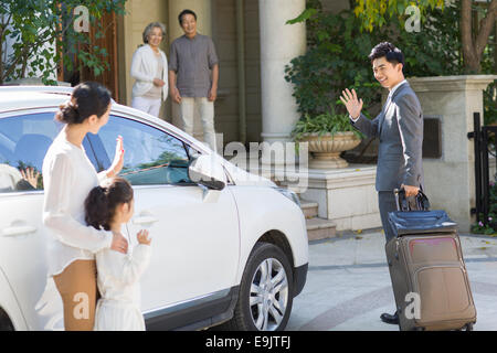 Mother and daughter waving goodbye to father Stock Photo