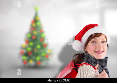 Composite image of smiling woman wearing santa hat Stock Photo