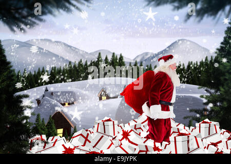 Composite image of santa walking on pile of gifts Stock Photo
