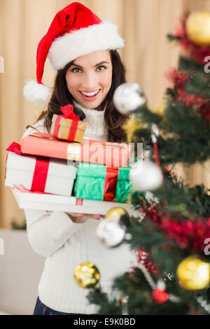 Festive brunette holding pile of gifts near a christmas tree Stock Photo