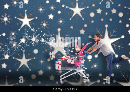 Composite image of man pushing woman in trolley Stock Photo