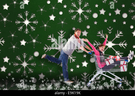 Composite image of man pushing woman in trolley Stock Photo