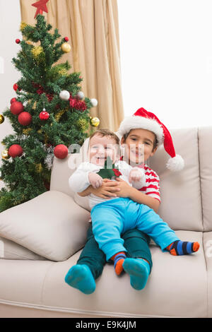 Cute boy and baby brother on couch at christmas Stock Photo