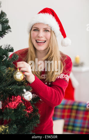 Smiling woman hanging christmas decorations on tree Stock Photo