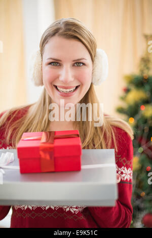 Smiling blonde wearing earmuffs while holding gifts Stock Photo