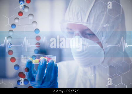 Composite image of scientist in protective suit analyzing pills Stock Photo
